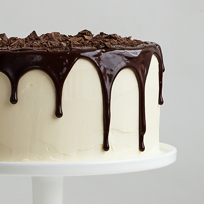white icing cake on pedestal dripping dark chocolate icing