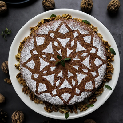 top view of powder sugar dusted snowflake pattern on dark round cake